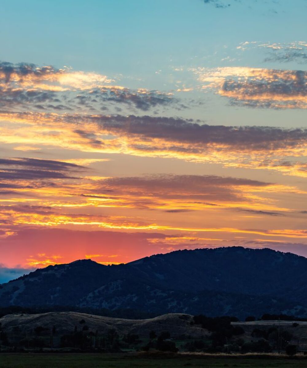 Vibrant sunset over mountains with colorful clouds in a stunning twilight scene.
